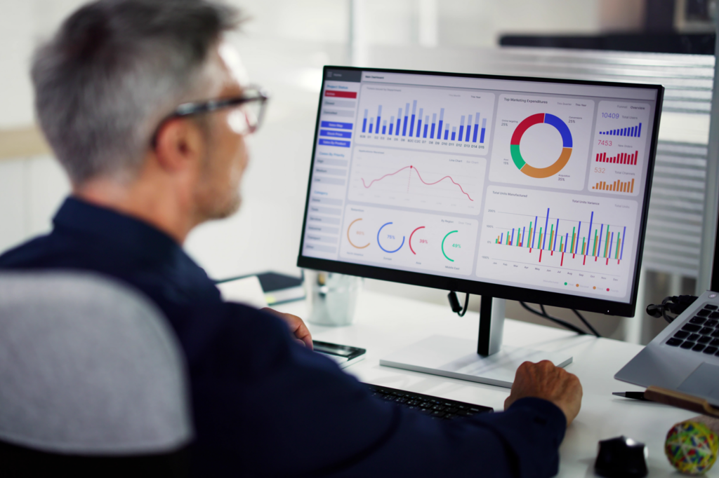 A facilities leader sitting at a desktop creating an asset management plan.