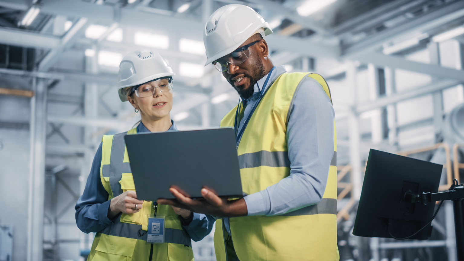 Employees analyze a laptop in a factory to monitor their assets with eam cmms.