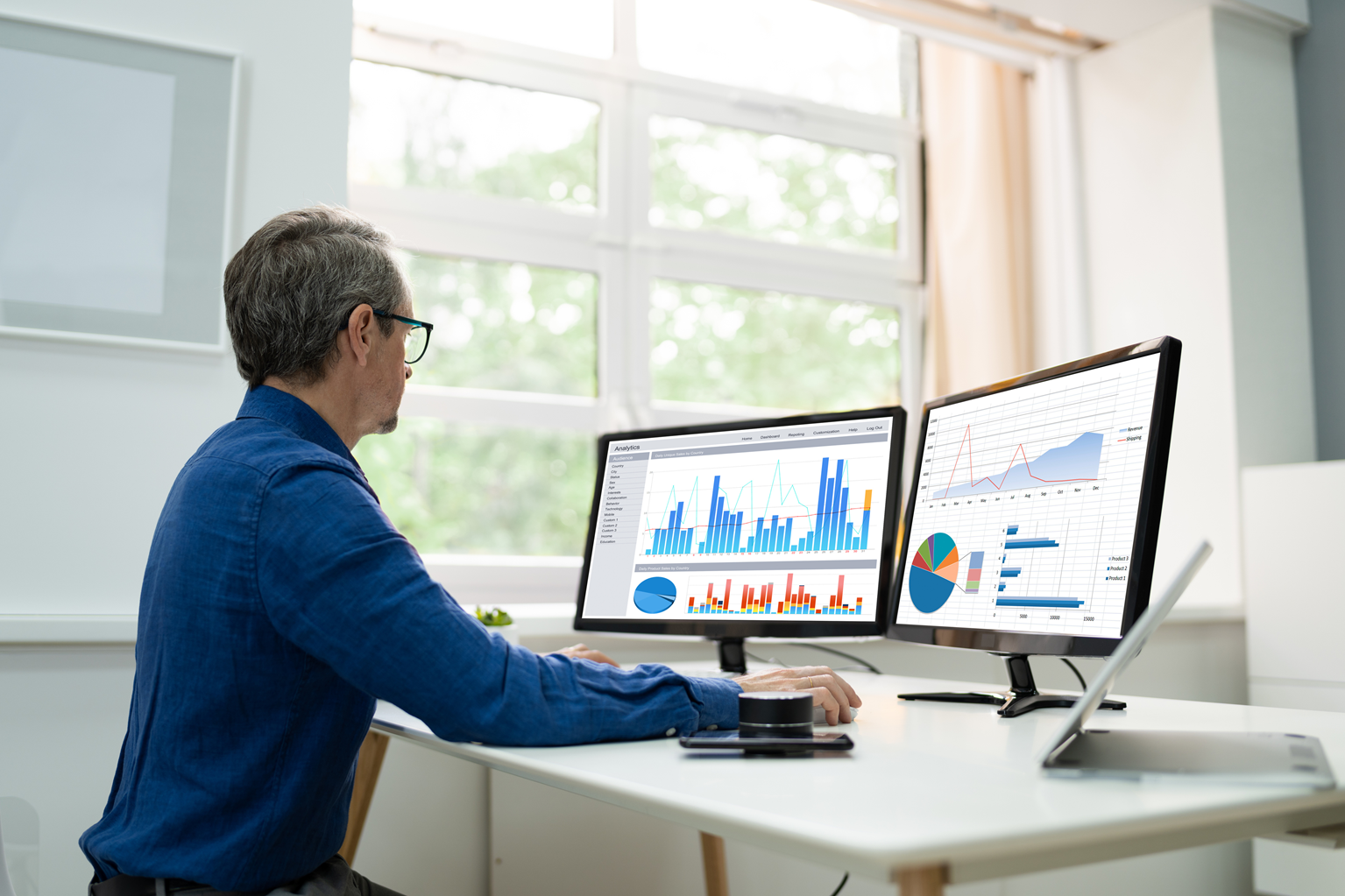 A man sits at a computer looking over fixed asset depreciation data.